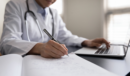 women writing notes with laptop